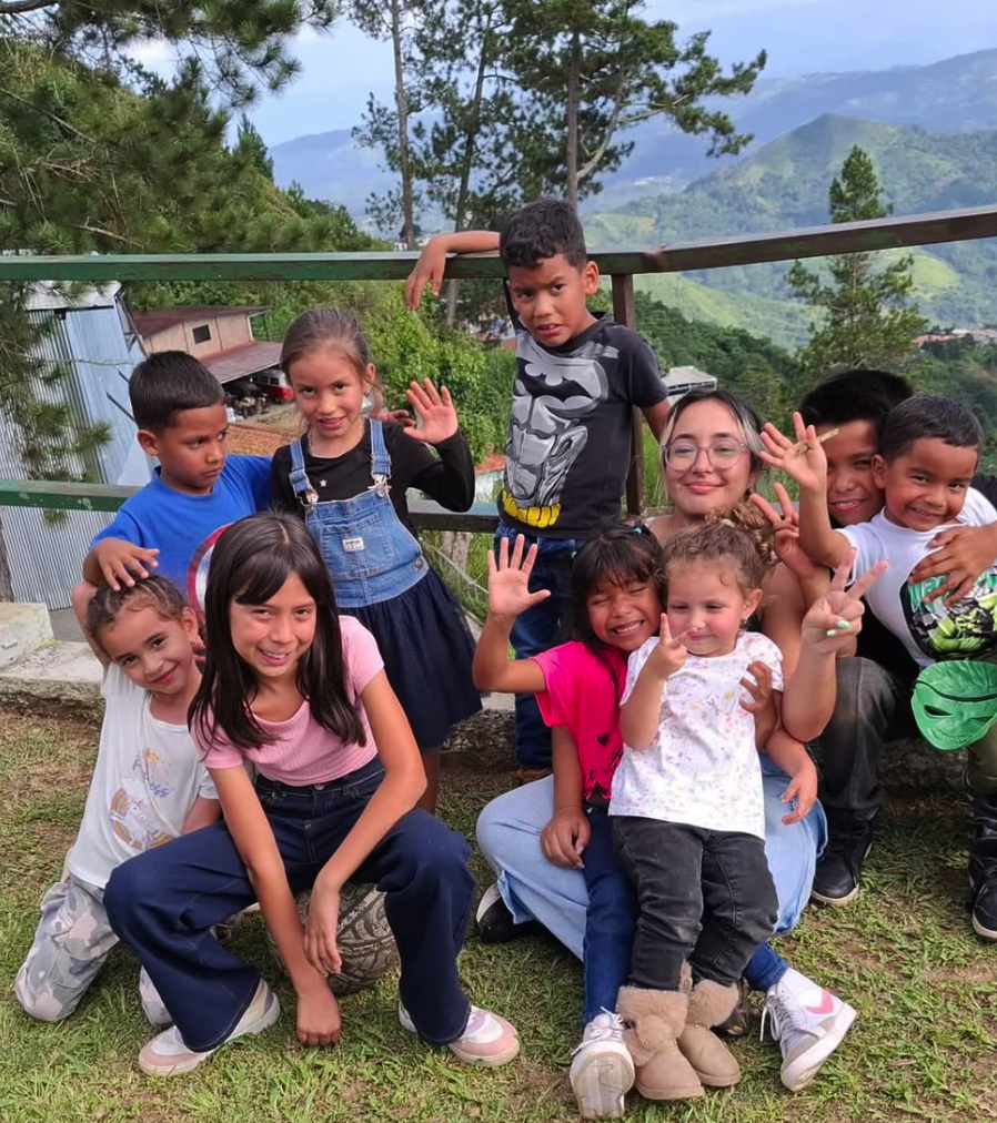 Children of Asociación Nueva Esperanza smiling together with their caregiver in the Venezuelan mountains